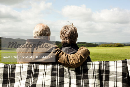 Back view of senior couple enjoying scenery on field Back view of senior couple enjoying scenery on field
