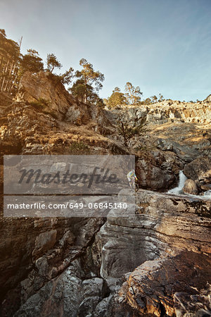 Man mountain biking on rocks by cliffs