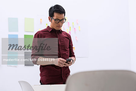 Young male with smartphone in design studio Young male with smartphone in design studio