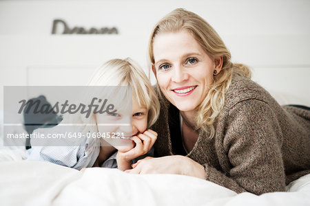 Portrait of mother and son lying on bed