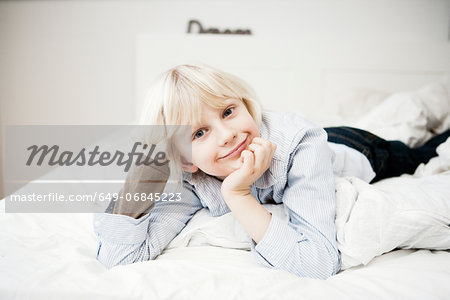 Portrait of young boy lying on bed