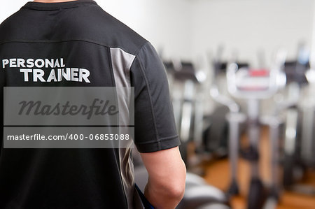 Personal Trainer, with his back facing the camera, looking at a gym