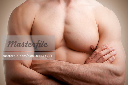 Close up of a muscular male torso, arms crossed