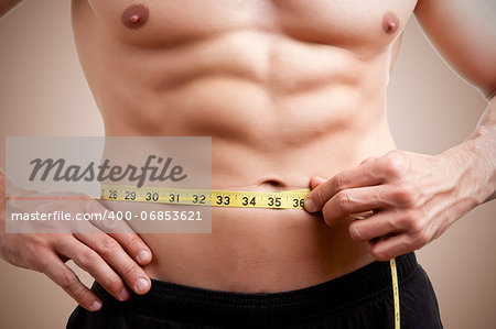 Fit man measuring his waist after a workout in the gym