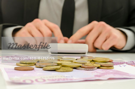 Front view of financial adviser working. With Euro banknotes and coins on his desk. Focus on money.