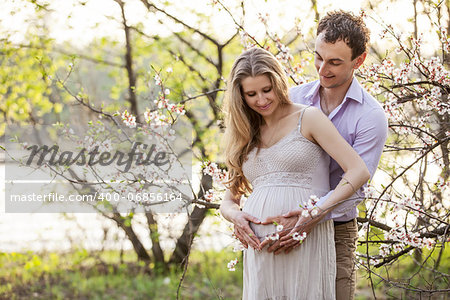 Young pregnant couple outdoors in spring blossom