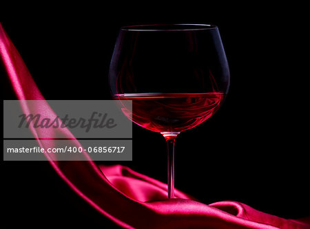 Glass of wine on red silk with dark background