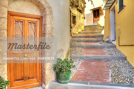 Wooden door at the entrance to small house on narrow cobbled street in town of Ventimiglia in Liguria, Italy.