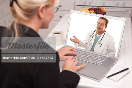 Woman In Kitchen Using Laptop - Online Chat with Nurse or Doctor on Screen.