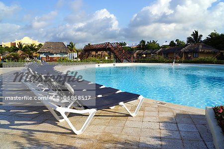 Plank beds and chaise lounges nearby on territories of the pool, a palm tree and other structures in a recreation area