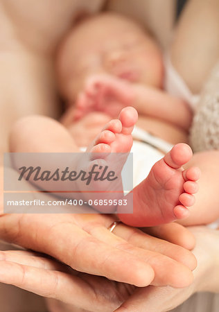 Newborn baby in mother's arms, closeup view, feet in focus
