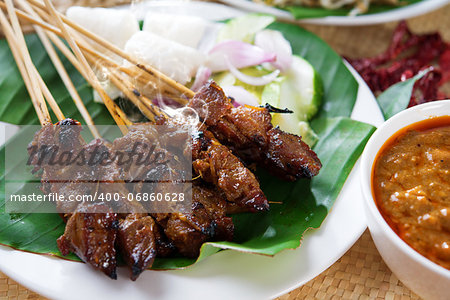 Satay or sate, skewered and grilled meat, served with peanut sauce, cucumber and ketupat. Traditional Malay food. Delicious hot and spicy Malaysian dish, Asian cuisine.