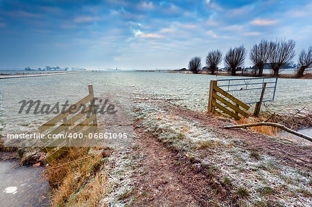 wooden fence on winter pasture at sunrise