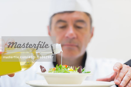 Salad being dressed by chef in kitchen