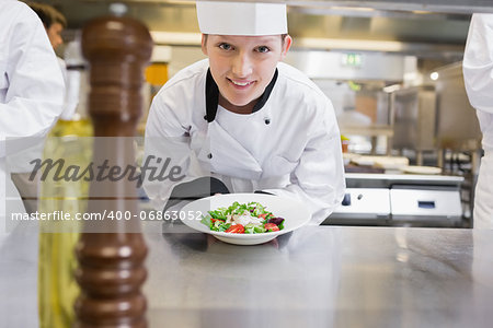 Happy chef presenting her salad in the kitchen