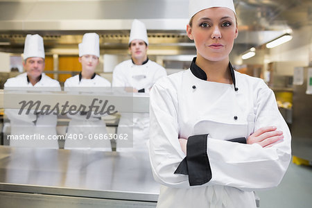 Chef standing with crossed arms with team standing behind