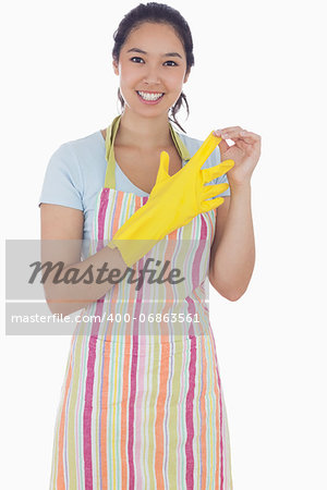 Smiling woman in apron taking off rubber gloves