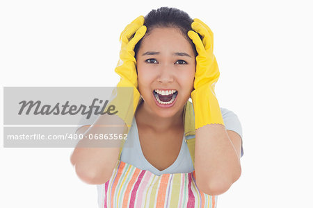 Distressed woman with hands on her head wearing apron and rubber gloves and screaming