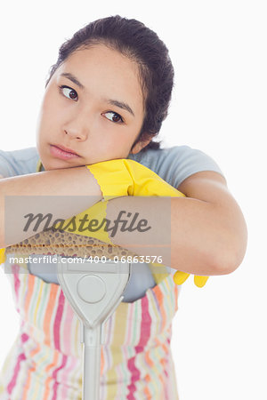 Fed up woman wearing apron leaning on the mop