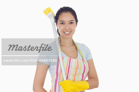 Happy woman in gloves with broom on her shoulder