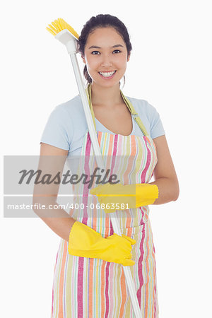 Smiling woman in yellow gloves with a broom on her shoulder