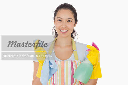 Smiling woman holding cloth and spray bottle in apron and rubber gloves