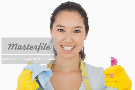 Smiling woman in rubber gloves with cloth and spray bottle