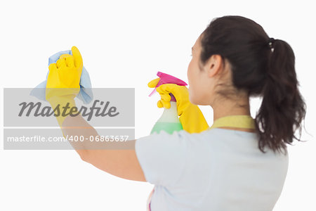 Brunetter woman spraying and wiping in rubber gloves