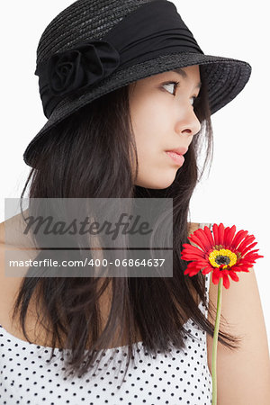 Woman with flower looking away wearing hat and polka dots on white background