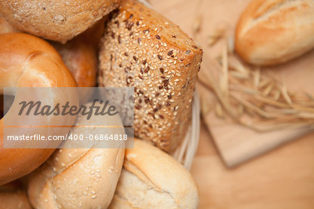 Diffferent bread in the basket with a roll on a wooden board