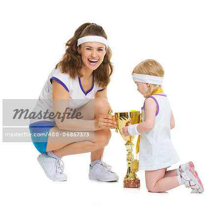Happy mother and baby in tennis clothes with medal and goblet