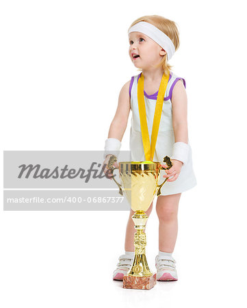 Happy baby in tennis clothes with medal and goblet looking on copy space