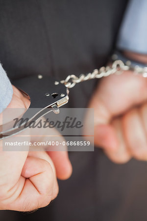 Closeup of businessman with handcuffs clenching fists