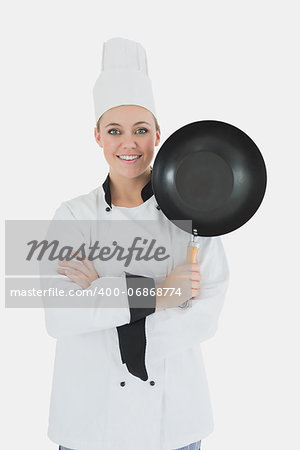 Portrait of confident female chef with arms crossed holds frying pan over white background