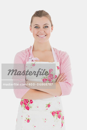 Portrait of young woman in apron with arms crossed over white background