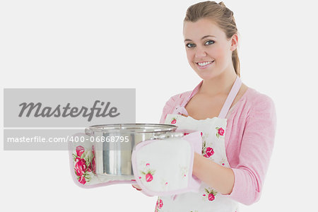 Portrait of happy young maid holding cooking utensil over white background
