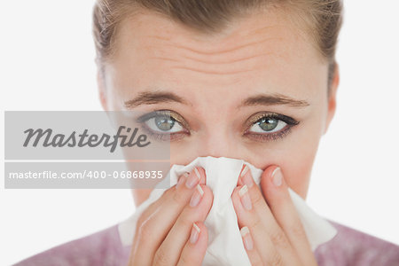 Portrait of young woman suffering from cold against white background