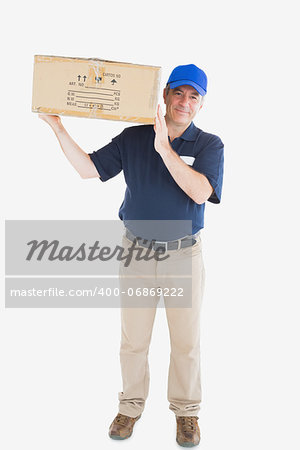 Portrait of mature courier man carrying cardboard box against white background