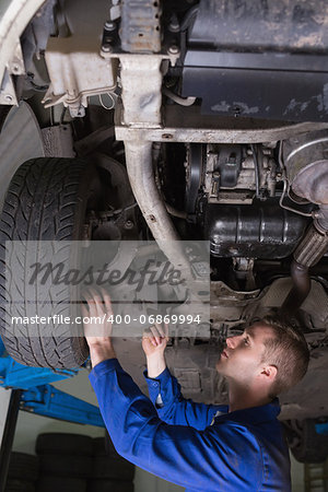 Male mechanic working under car in garage