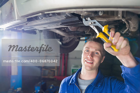 Portrait of happy male mechanic repairing car with pliers