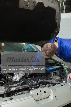 Male mechanic working under bonnet of car