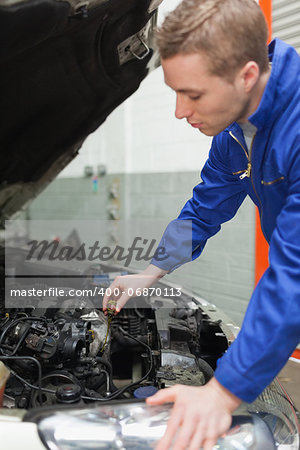 Male mechanic checking car engine oil
