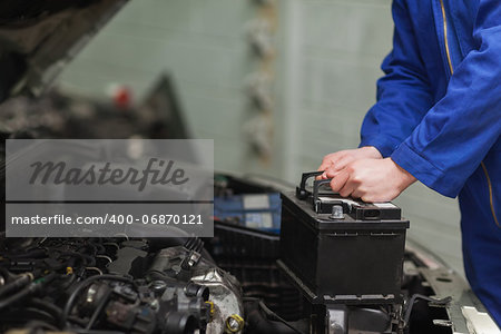 Male mechanic changing car battery