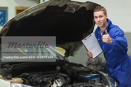 Portrait of male mechanic with clipboard gesturing thumbs up