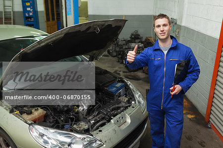 Portrait of male mechanic by car gesturing thumbs up