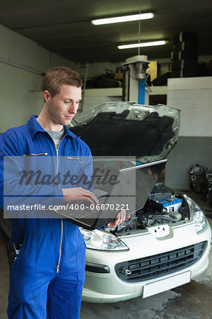 Male mechanic using laptop in auto repair shop