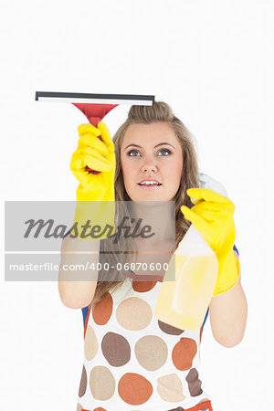 Beautiful young maid in yellow gloves using wiper and disinfectant spray over white background