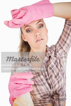 Portrait of tired young woman holding spray bottle over white background