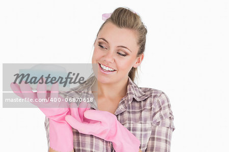 Smiling young woman holding soap suds over sponge against white background