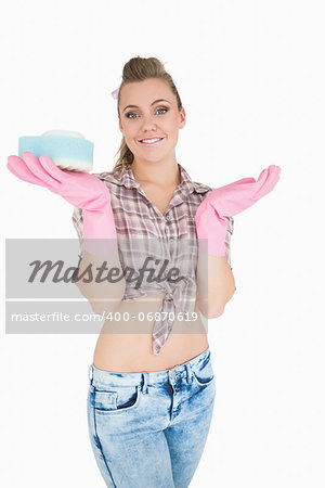 Portrait of smiling young woman holding soap suds over sponge against white background